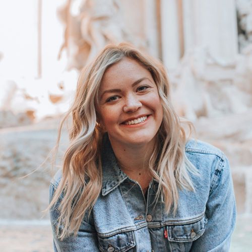 Eine lächelnde junge Frau mit blonden Haaren und einer Jeansjacke